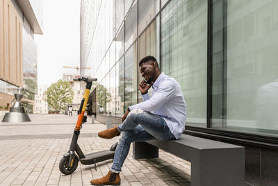 Young man talking on mobile phone sitting on bench