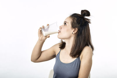 Portrait of a young woman drinking glass against white background
