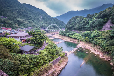 Scenic view of river amidst trees and mountains against sky