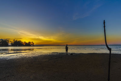 The silhouette of the tourist standing watching the sunrise at laem ta chi, pattani, thailand.