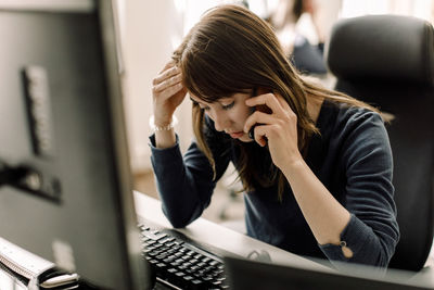 Computer programmer talking on phone at workplace