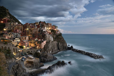 Panoramic view of rough sea and manarola buildings against sky in cinqueterre