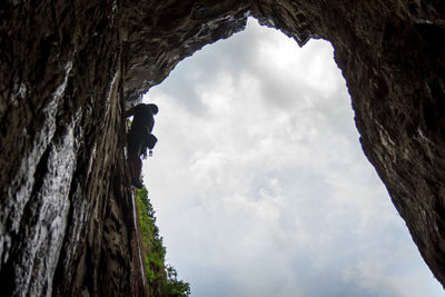 Low angle view of man on rock formation against sky