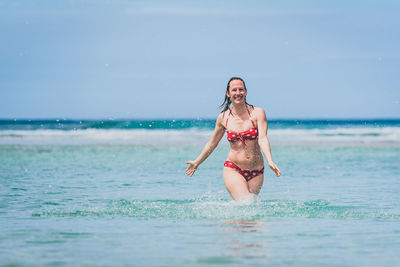 Portrait of happy mid adult woman in sea against sky