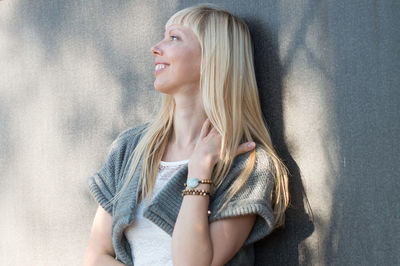 Smiling young woman standing against wall