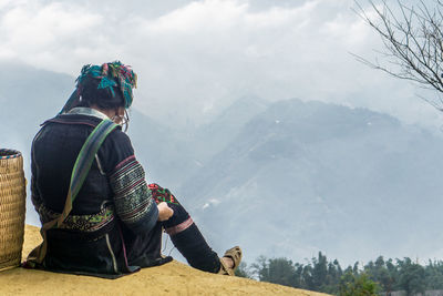 Rear view of people looking at mountains against sky