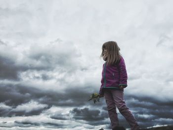 Rear view of girl standing against cloudy sky