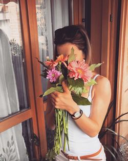 Woman covering her face with flowers at balcony