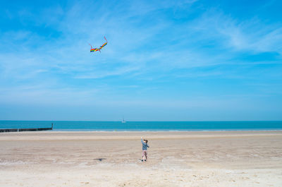 Child on beach against blue sky