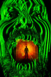 Digital composite image of silhouette man in illuminated green mouth