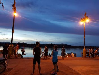 People on street against sky during sunset