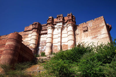 Low angle view of mehrangarh fort against clear blue sky