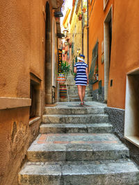 Rear view of woman walking on steps in alley