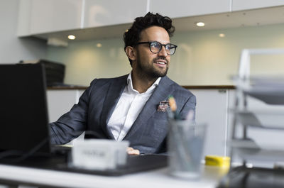 Thoughtful male real estate agent sitting at desk in office