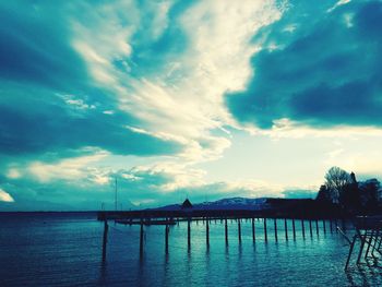 Pier on sea against cloudy sky