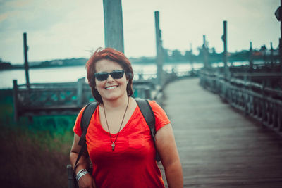 Portrait of smiling young woman standing by railing