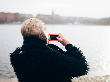 Rear view of woman photographing against sky