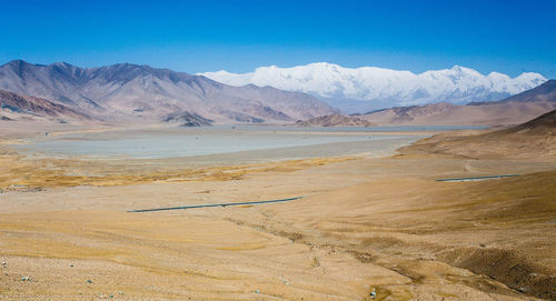 Scenic view of landscape and mountains against blue sky