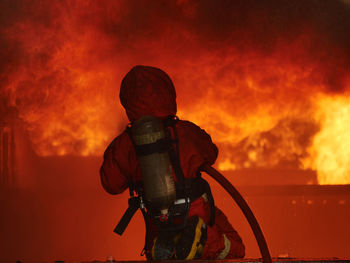 Rear view of person photographing against orange sky