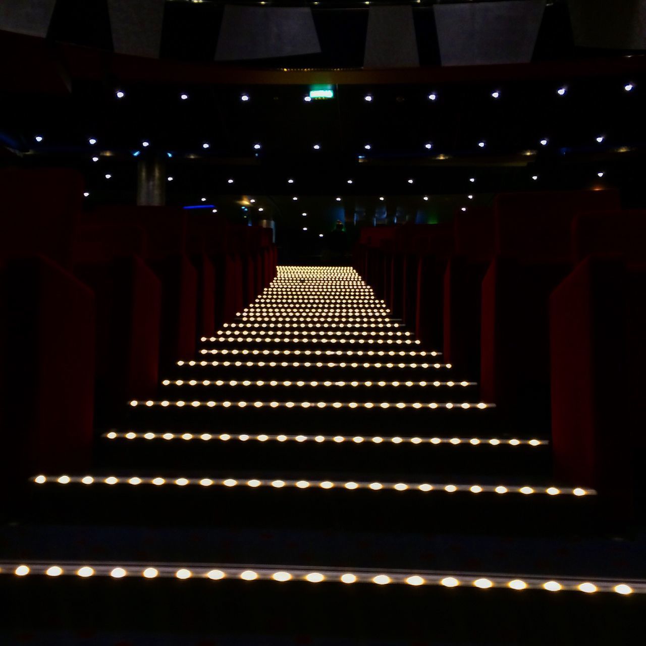 indoors, in a row, lighting equipment, no people, repetition, arts culture and entertainment, auditorium, low angle view, illuminated, seat, architecture