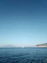Sailboat sailing on sea against clear blue sky