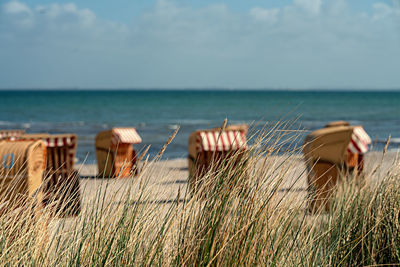 Deck chairs on beach against sky