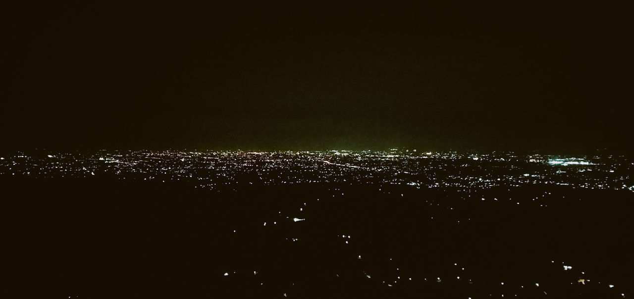 AERIAL VIEW OF ILLUMINATED CITY AGAINST SKY AT NIGHT