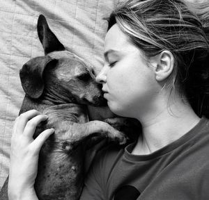 Directly above shot of woman lying down with dog on bed