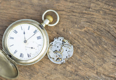 High angle view of broken pocket watch on wooden table