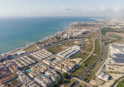 High angle view of cityscape by sea against sky