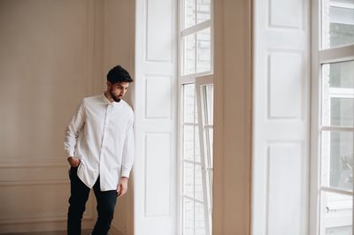 Groom standing by window at home