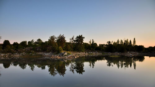 Reflection of trees in lake against clear sky