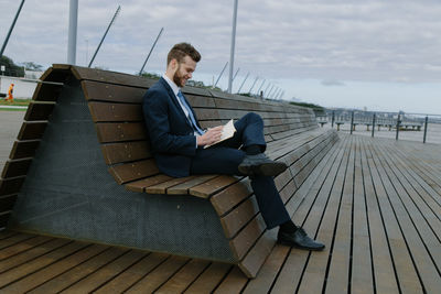 Young businessman writing in book while sitting on bench
