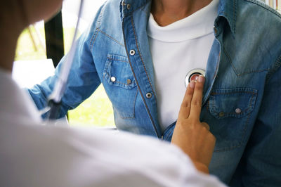 Midsection of female doctor examining patient using stethoscope in hospital