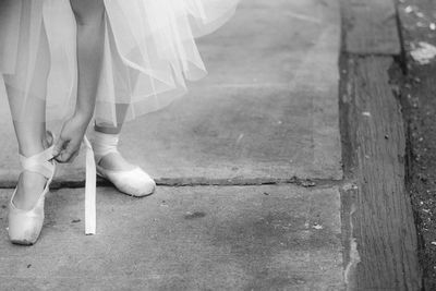 Low section of woman wearing ballet shoes on sidewalk