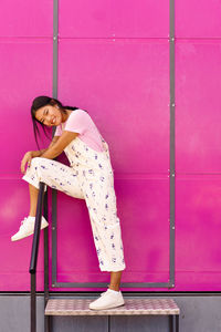 Portrait of young woman standing against wall