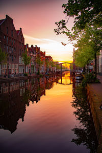 Canal amidst buildings against sky during sunset