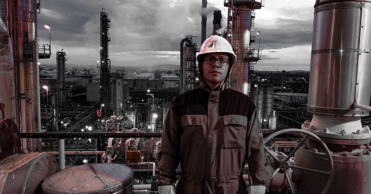 industry, one person, occupation, helmet, portrait, factory, oil industry, refinery, front view, looking at camera, real people, headwear, fuel and power generation, standing, men, hardhat, working, business, oil refinery