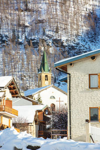 Snow covered houses by trees and buildings