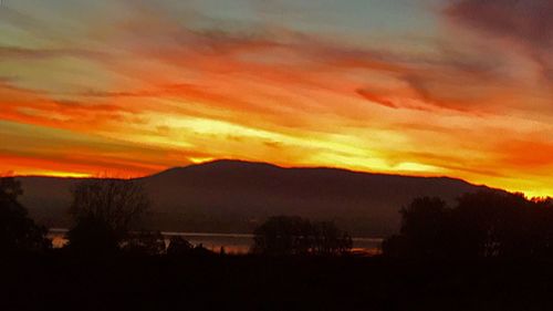 Scenic view of silhouette mountains against sky at sunset