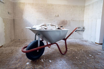 Abandoned shopping cart on floor against wall at home