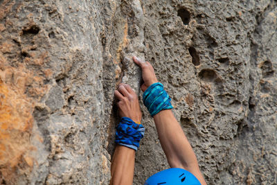 Close-up of man rock climbing against sky