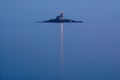 Lighthouse amidst sea at dusk