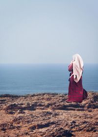 Rear view of woman looking at sea against clear sky