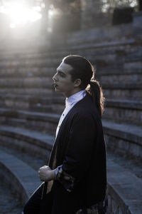 Young male model standing on steps during sunset