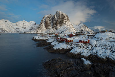 Scenic view of snowcapped mountains by sea against cloudy sky