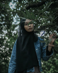 Young woman standing by tree against plants