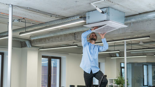 Caucasian bearded man repairing the air conditioner in the office