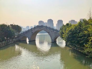 Bridge over river in city against sky