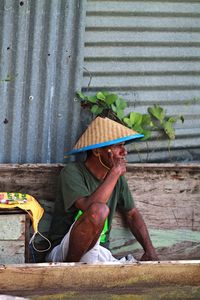 Man smoking on floating market by corrugated iron